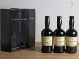 three bottles of wine sitting on top of a wooden table next to a black box