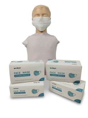 une personne portant un masque à côté de trois boîtes de masques jetables