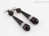 une paire de boucles d'oreilles en verre à rayures noires et blanches sur fond blanc
