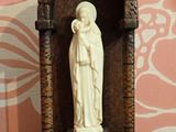 une statue représentant une femme tenant un enfant dans ses bras devant un mur
