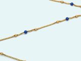 a close up of a gold chain with blue beads on it