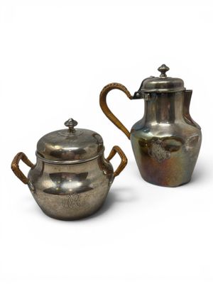 pair of silver plated teapots with handles and a lid