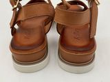 a close up of a pair of brown sandals on a white surface