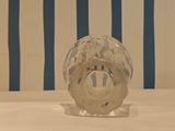 a glass vase sitting on a table with a striped wall behind it