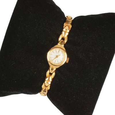 un gros plan d'une montre en or posée sur un coussin en velours noir