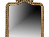 un miroir à cadre doré orné d'un motif décoratif dans sa partie supérieure