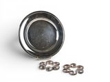 a small metal bowl with rings in it on a white surface