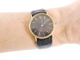 a black and gold watch on a woman ' s wrist