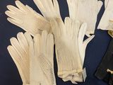 three pairs of white gloves and a black purse on a blue surface