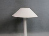 une lampe de table blanche posée sur une table près d'un mur gris