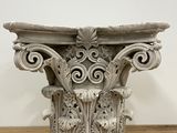 a close up of a white corin column on a wooden table