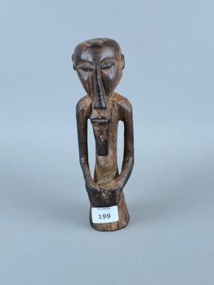 une vieille figurine en bois représentant un homme tenant une bouteille