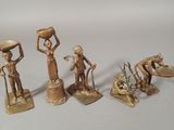 four bronze figurines of a woman with a basket on her head and a man holding a bowl on his head