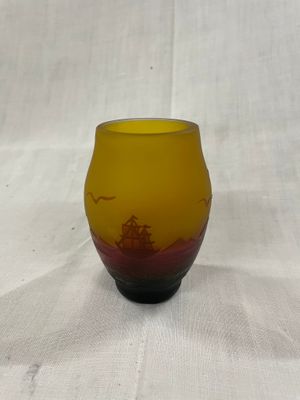 un vase en verre jaune et rouge posé sur une table blanche