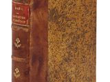 un vieux livre à la couverture brune posé sur une surface blanche