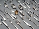 un grand nombre de cuillères et de fourchettes disposées sur la table