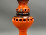 an orange ceramic lamp with holes on the base and a cord plugged into the base