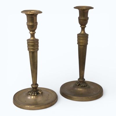 Deux FLAMBEAUX en bronze, le fût à pans reposant sur trois p…