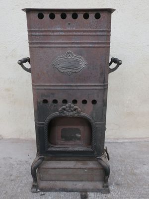 an old stove sitting on the sidewalk in front of a white wall
