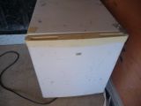 a small white refrigerator sitting in the corner of a room