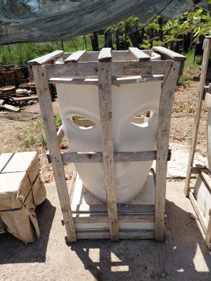 a white toilet sitting on a pallet next to a pile of boxes