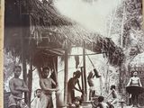 an old black and white photo of a group of men in front of a hut