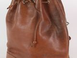 une photo d'un sac seau en cuir marron posé sur une surface blanche