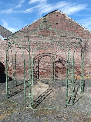 a green metal gazebo sitting in front of a brick building