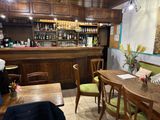 tables and chairs in a restaurant with a bar in the background