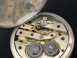 a silver pocket watch with gears inside of it