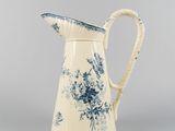 blue and white pitcher with flowers on it on a gray background