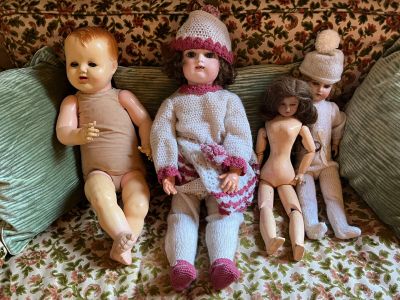 five dolls sitting on a couch with a green pillow