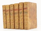 quatre vieux livres posés l'un sur l'autre sur une surface blanche
