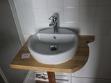 a white sink sitting on a wooden counter in a bathroom