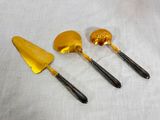 three pieces of gold colored utensils on a white cloth