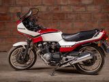 a red and white motorcycle parked in front of a brick wall