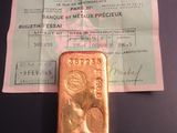 un lingot d'or posé sur une feuille de papier, à côté d'un ticket de caisse
