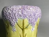 a yellow vase with purple flowers on it sitting on a table