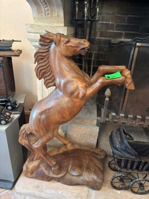 une statue représentant un cheval tenant un frisbee vert dans la bouche