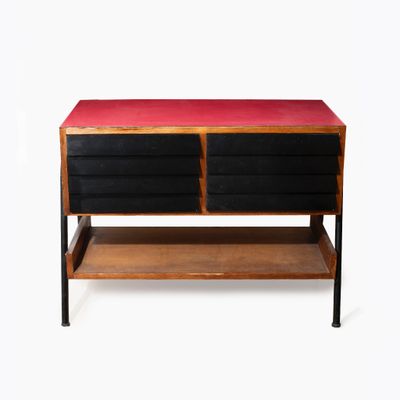 une photo d'une commode noire et rouge posée sur une étagère en bois