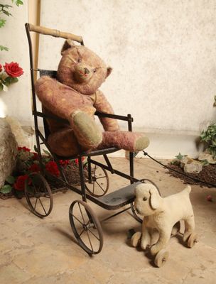 un ours en peluche assis dans une poussette à côté d'un petit chien