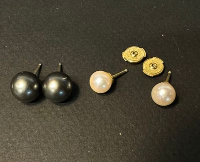 three pairs of pearl and gold earrings on a black surface