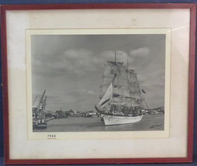 une vieille photo d'un voilier sur l'eau, avec un quai en arrière-plan