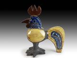une sculpture en céramique représentant un coq à la tête bleue et jaune