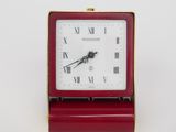 a small red clock with roman numerals on it