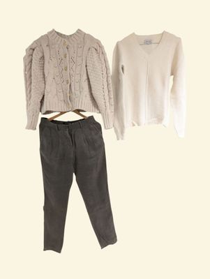 two sweaters and pants on a hanger next to each other