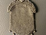 an antique silver mesh purse with pearls hanging from it