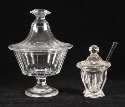 deux bocaux en verre transparent avec leurs couvercles et leurs cuillères, posés sur une surface noire