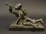 bronze statue of a man laying on a rock with a trumpet