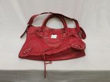 a red handbag on a white table with a white background